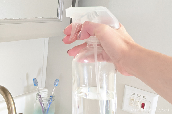 woman cleaning her bathroom mirror with homemade window cleaner